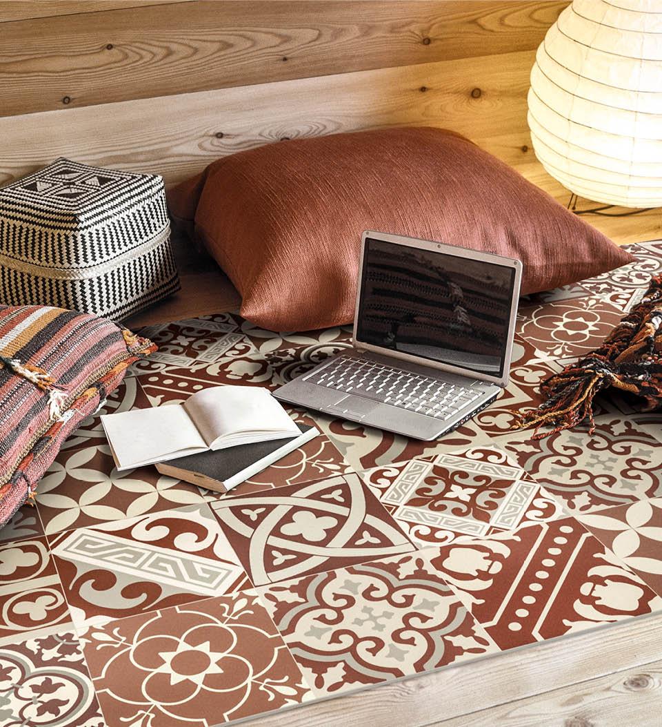 Intricately patterned rug under scatter cushions, a laptop and notebooks