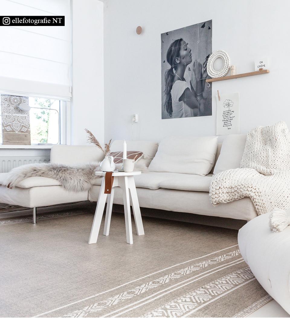 A beige rug with African traditional print placed under a stool and an L-shaped couched 
