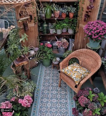 A patio with a floral rug and a chair surrounded by plants and flowers