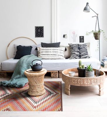 A colorful patterned kilim-style rug on the living room floor under a wicker coffee table in front of a white sofa