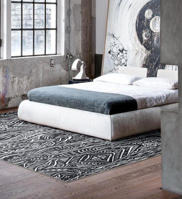 A street-style patterned rug in black and white under a bed