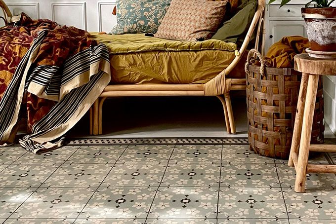 Wooden chair with mustard colored covering on tile patterned vinyl rug