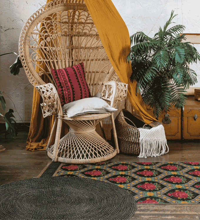A colorful runner rug paired with a round brown rug under a wicker chair