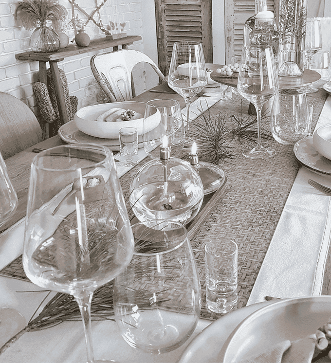 A dinner table decorated for Christmas in white colors with wine glasses