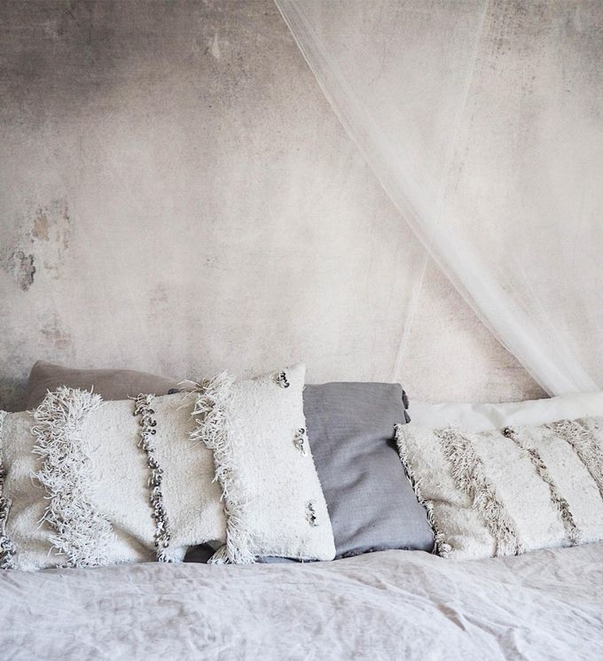 A concrete-texture wall art piece above a bed with pillows