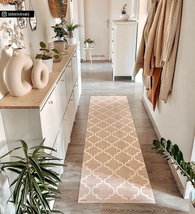 An elegantly patterned rug in beige and white in a hallway next to a dresser