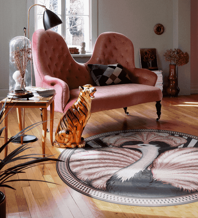A round rug with pink-feathered ostrich print on a living room floor