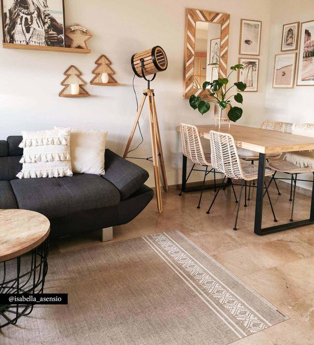 A neutral beige rug with a pattern on the border on an open floor space living room area floor