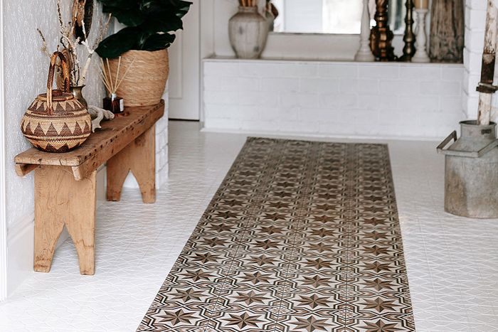 Custom floor rug in decorative white hallway next to wooden bench and woven baskets