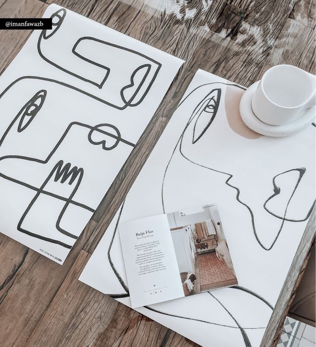White placemats with an artistic design of a Picasso-style face on a wooden table with a Beija Flor catalog