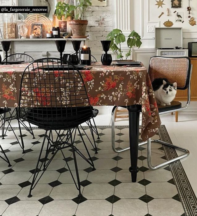 Black and white chessboard-pattern rug under a dining table with a floral tablecloth