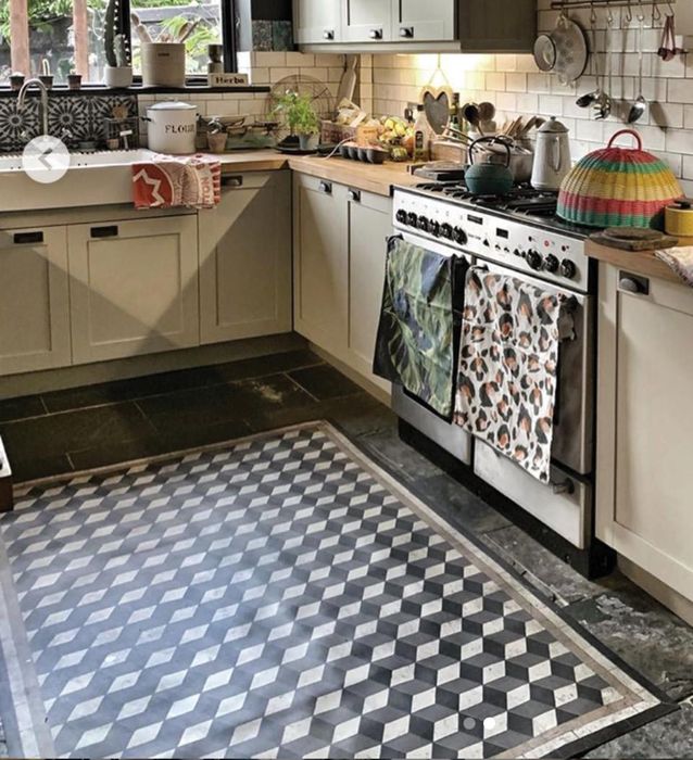 A Bauhaus-style patterned black and white rug on a kitchen floor in front of the sink