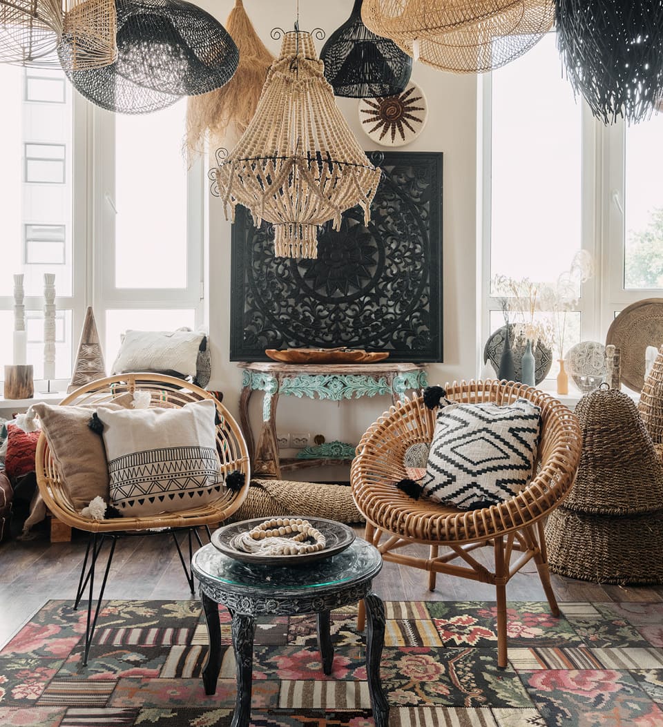 A room with two wicker chairs and a kilim-style colorful rug