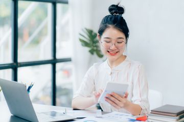 Woman using calculator and laptop at desk