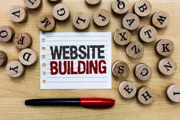 Letter tokens surrounding pen and paper with the text "Website Building" written on it