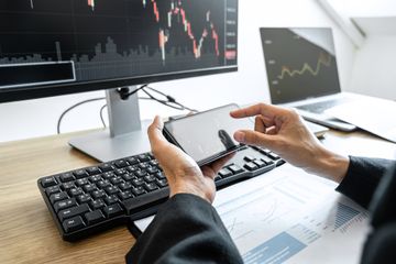 Man holding phone in front of pc