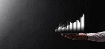 A businessman holding his cellphone with a graph showing an increase in value