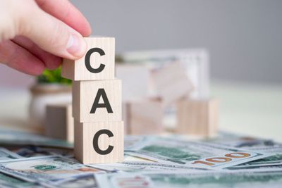 A person placing wooden blocks, featuring the letters CAC, on top of each other.