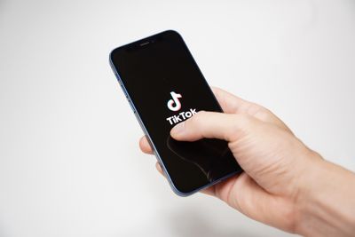 Hand holding a phone with TikTok logo on display