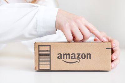 A person's finger pressed down on Amazon box package