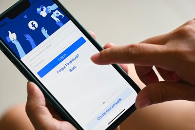 Person holding phone in hand with Facebook login page on display
