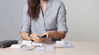 Woman reviewing multiple receipts with calculator in hand