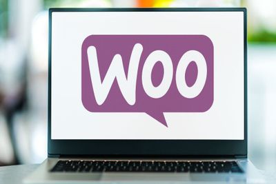A laptop screen displaying the WooCommerce logo in a purple speech bubble, against a white backrgound.