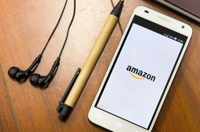 Cell phone logging into Amazon app next to pen and earphones