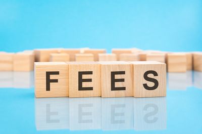 Word 'fees' being spelt out on 4 wooden blocks on a blue background