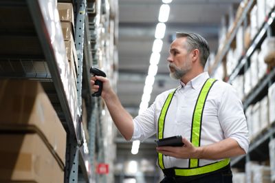 A man in a warehouse, scanning inventory for up-to-date tracking.