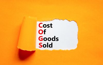COGS cost of goods sold symbol. Concept words COGS cost of goods sold on white paper on beautiful orange background. 