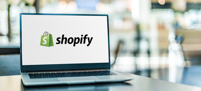A laptop on a table showcasing the Shopify e-commerce platform app on its screen
