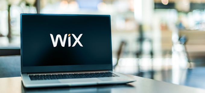 A laptop on a table showcasing the Wix e-commerce platform logo on its screen