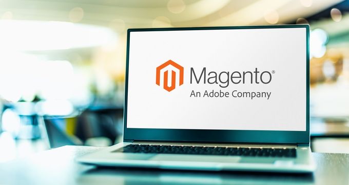 A laptop on a table showcasing the Magento e-commerce platform logo on its screen