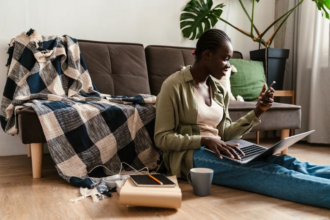 Woman sitting on the floor and using phone and laptop