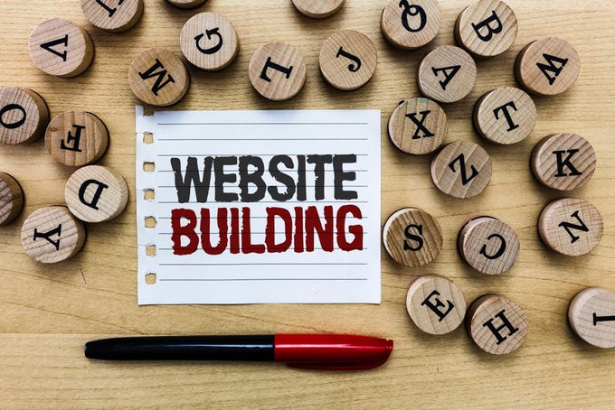 Letter tokens surrounding pen and paper with the text "Website Building" written on it