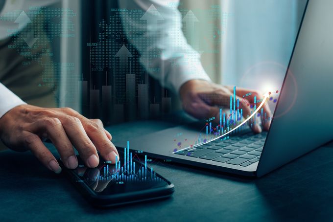 Man working on profit analysis with his cellphone and laptop on desk