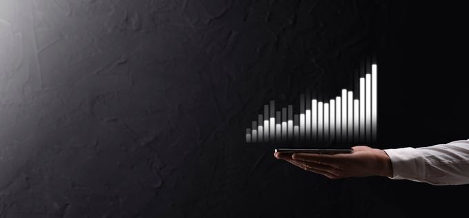 A businessman holding his cellphone with a graph showing an increase in value