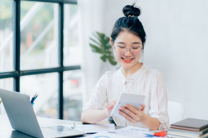 Woman using calculator and laptop at desk