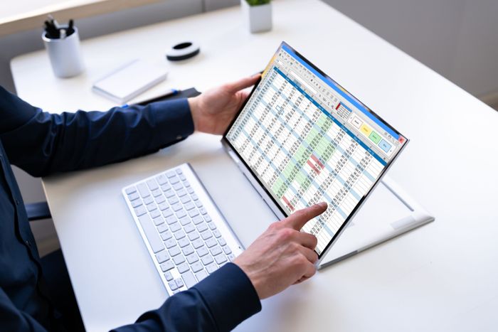 An analyst calculating the revenue in Excel on a tablet.
