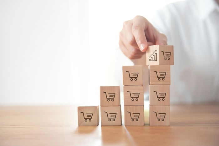 Man stacking blocks with painted shopping cart images and profit graphs