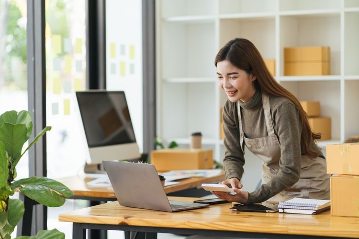 Woman at a desk using a calculator and laptop