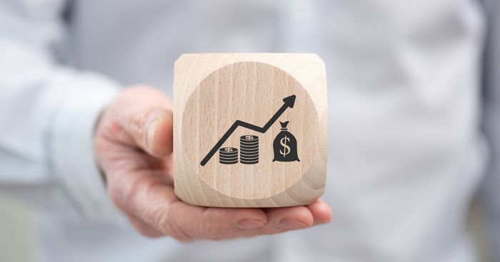 Man holding a wooden block with an image of an increasing profit graph