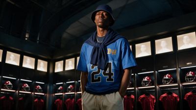a man in a football jersey stands in a locker room
