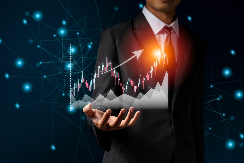 Businessman in suit holding virtual image of increasing graph with candlestick chart