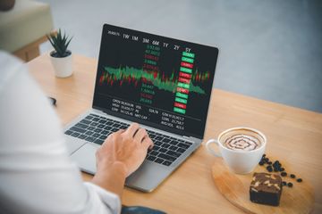 Man at laptop with coffee while day trading Forex