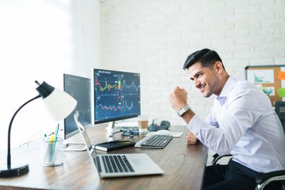 Young male trader looking at computer screen displaying stock graphs