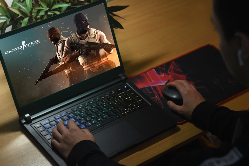Man sitting in front of gaming laptop loading Counter Strike: Global Offensive