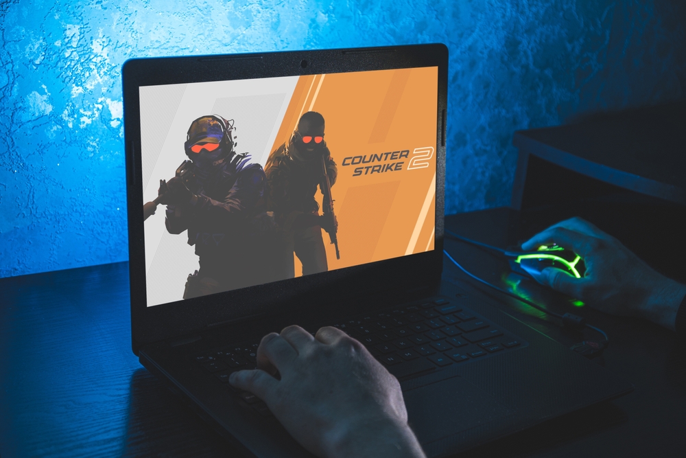 Gamer playing CS:GO on laptop with colorful gaming mouse and backlighting