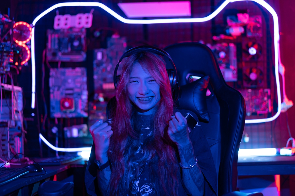 Girl in her gaming room surrounded by pink neon lights, looking happy after a victory